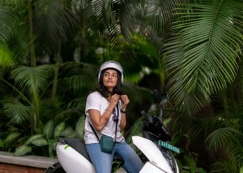 femme attachant son casque sur son scooter électrique