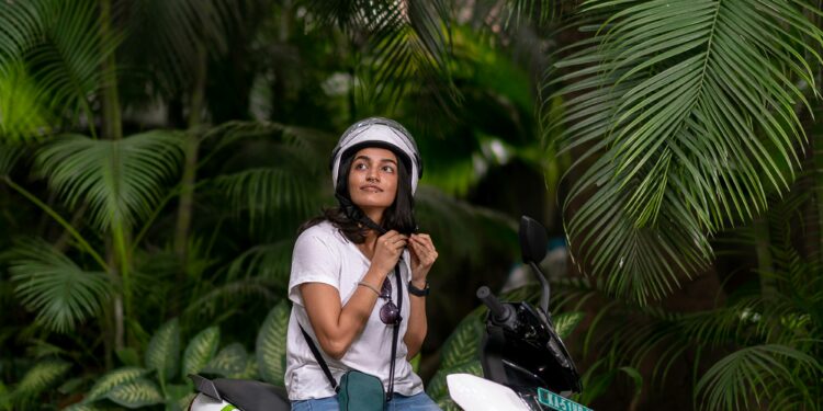 femme attachant son casque sur son scooter électrique