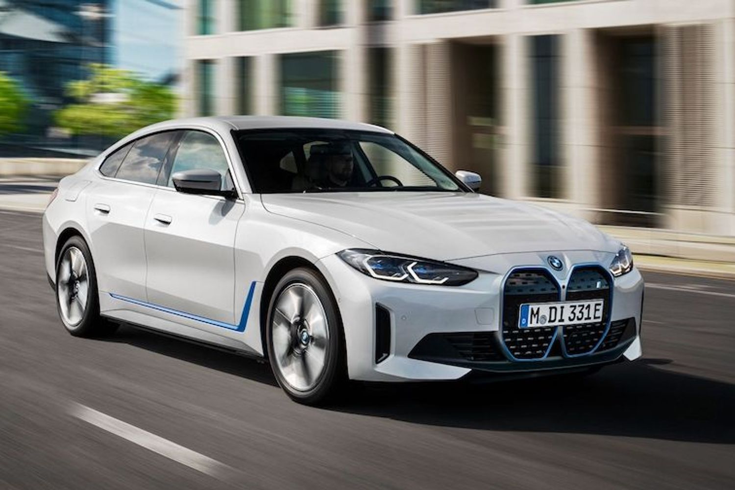 a white bmw car driving down a city street