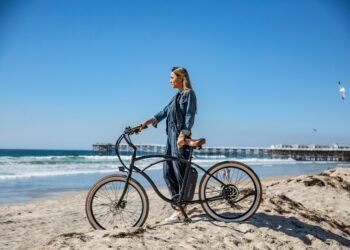 une femme avec son vélo à la main sur la plage