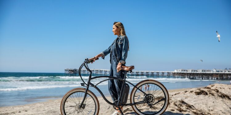 une femme avec son vélo à la main sur la plage